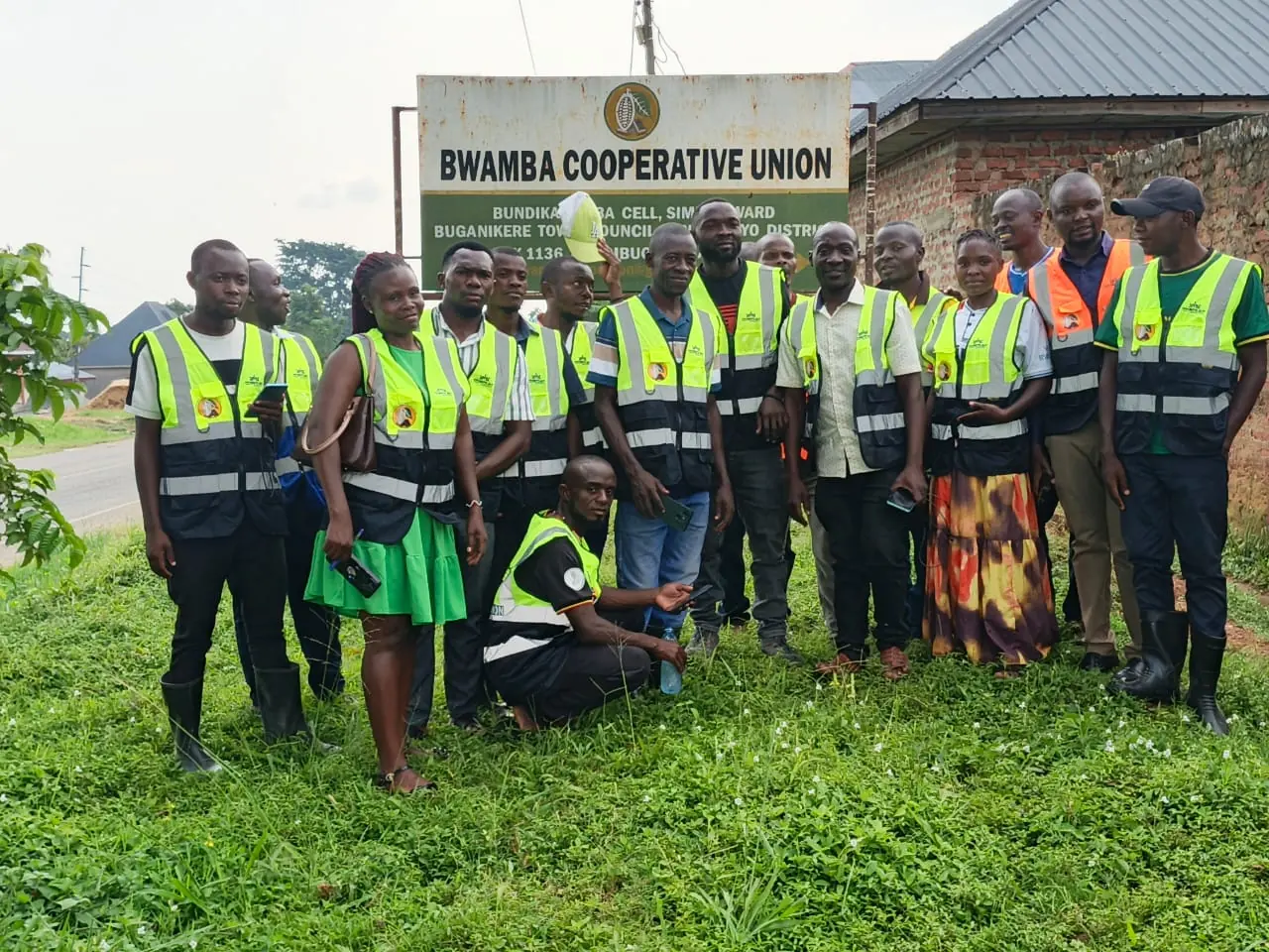 Bwamba Cooperative Union field officers in their vests in front of the union signboard